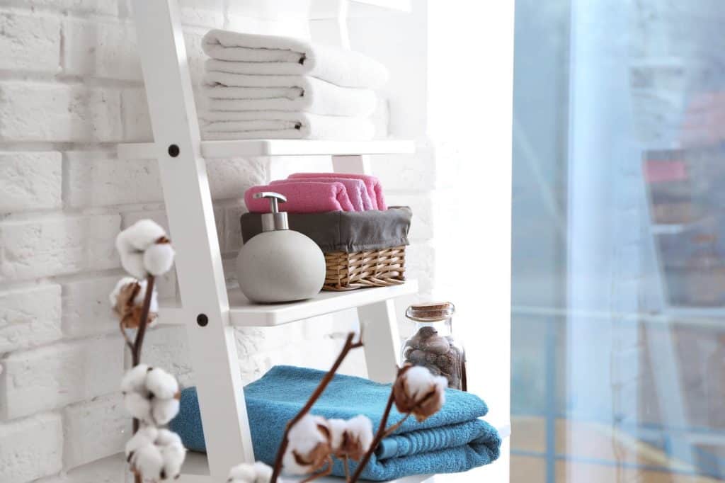 bathroom storage ladder with towels, soap and a storage basket