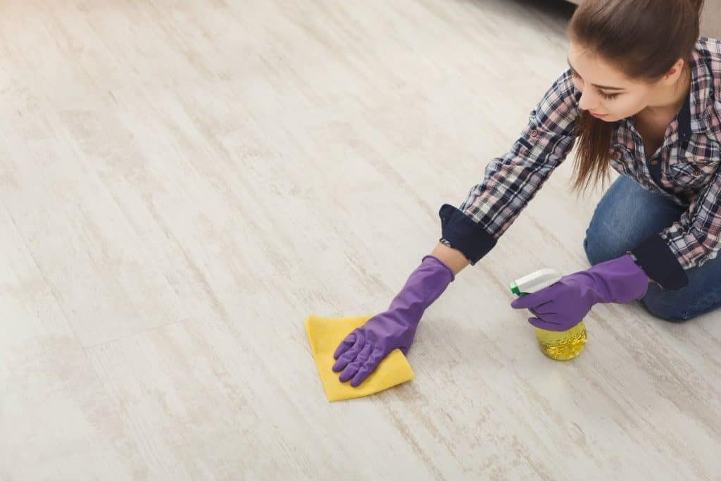 woman cleaning vinyl floor smudges with rubbing alcohol cleaning tip