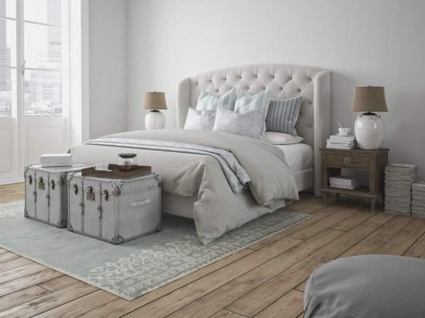 Decluttered bedroom with a neatly made bed, storage trunks and an area rug