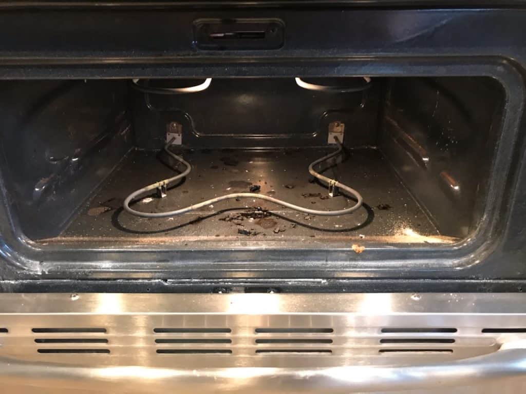 Dirty oven with burnt on food before being cleaned.