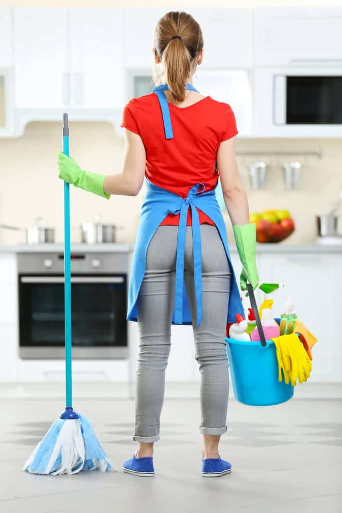 woman with cleaning supplies ready to deep clean the kitchen