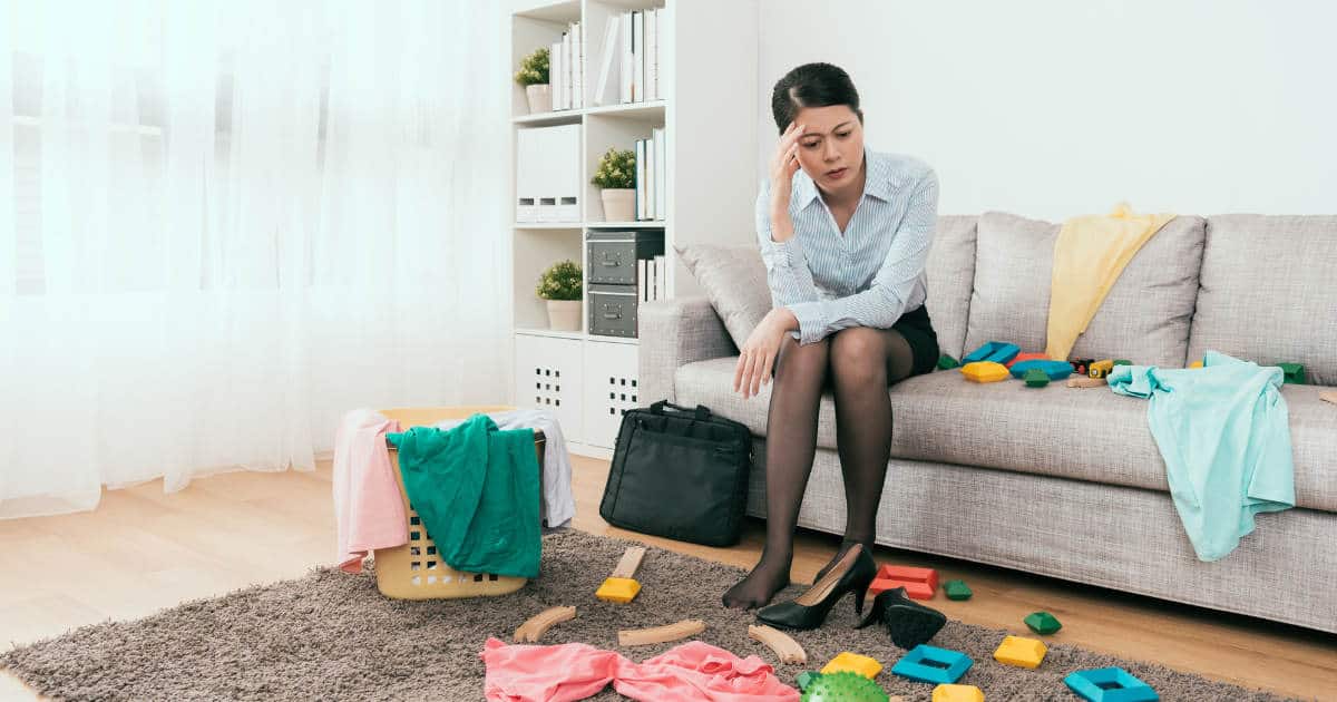 woman sitting in messy living room trying to figure out where to start decluttering