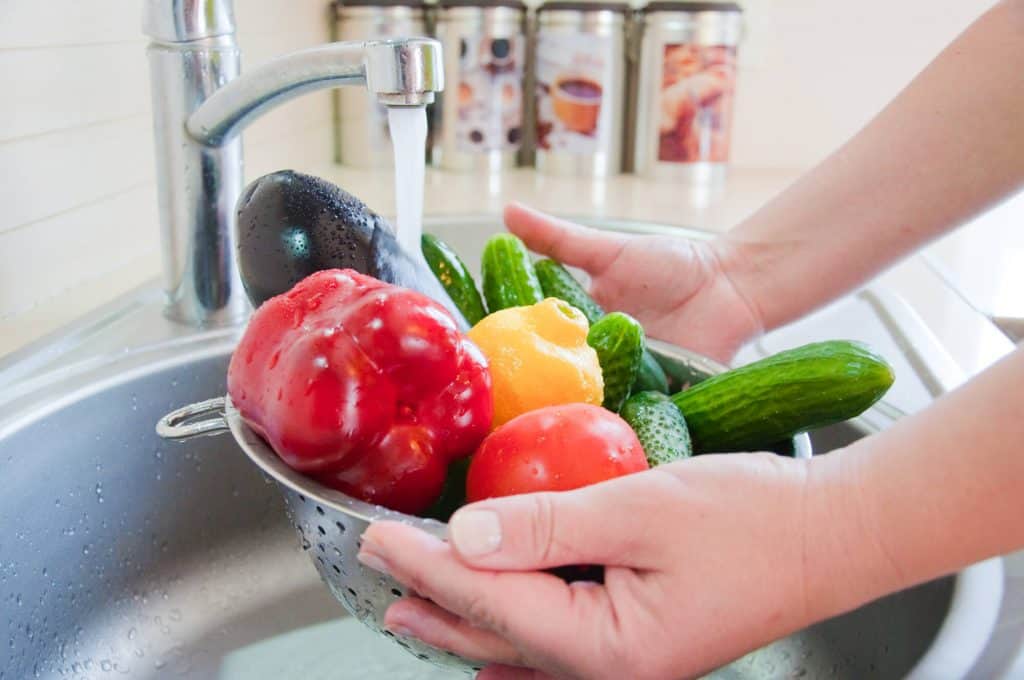 rinsing a strainer full of vegetables