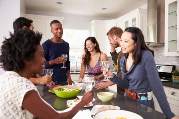 party guests snacking, drinking, and chatting in a kitchen