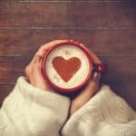 Woman in sweater holding warm cup of cocoa