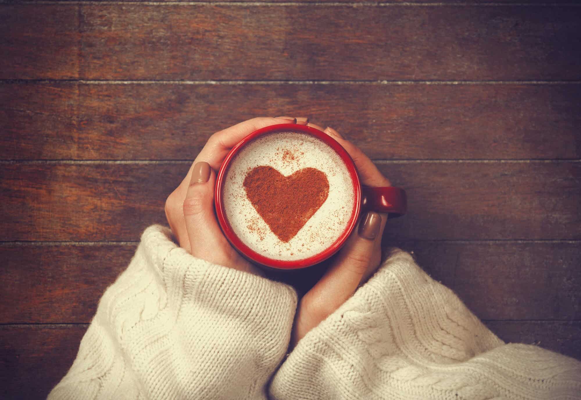 Woman in sweater holding warm cup of cocoa