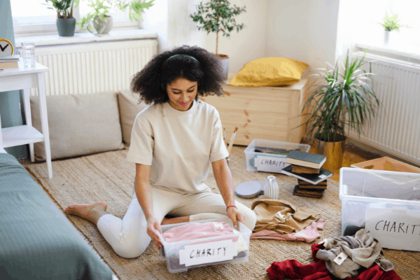 woman decluttering her closet and setting clothes aside for charity