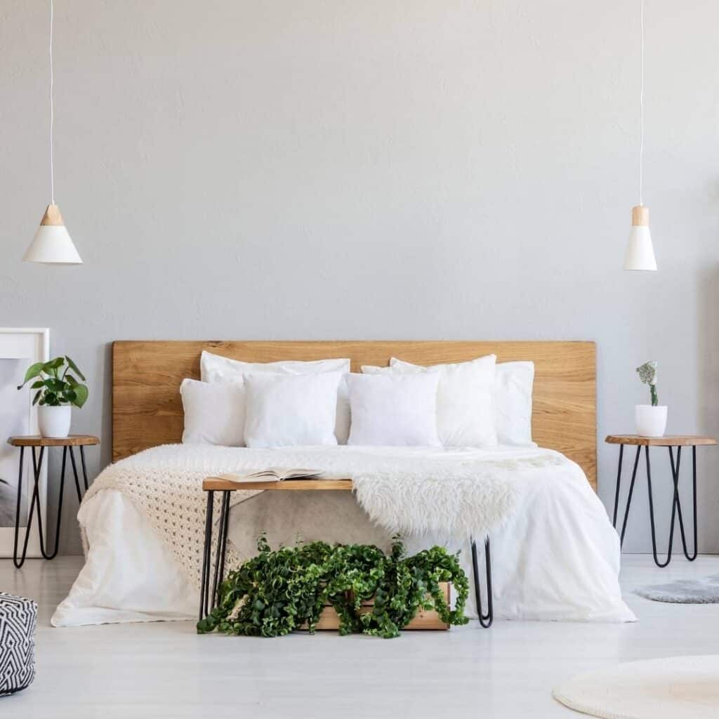 clean and tidy bedroom with white linens, light wood furniture and and light gray walls