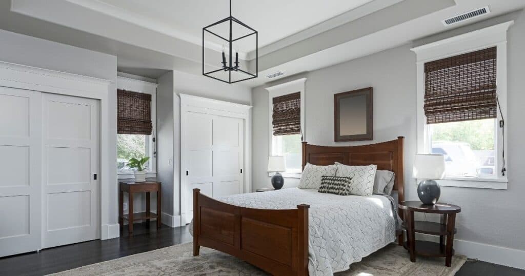 a clean and tidy master bedroom with light gray walls, white trim and dark hardwood floors