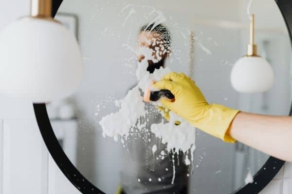 cleaning the bathroom mirror with shaving cream to prevent fogging