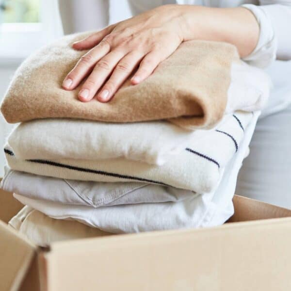 stack of unwanted clothing being put in a box for donation