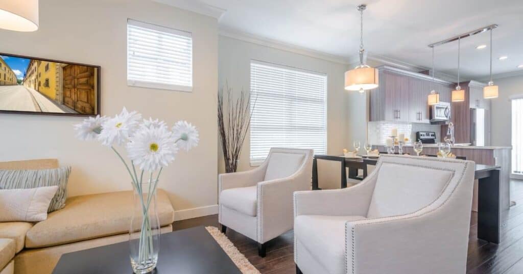 a clutter-free living room with white furniture and a vase of flowers on the coffee table