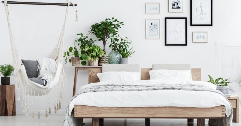 clean and spacious bedroom with white decor, green plants and a platform bed