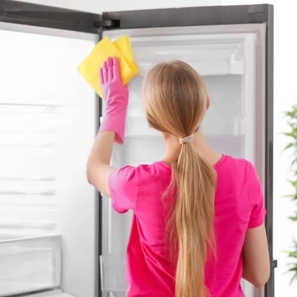 woman deep cleaning the fridge interior surfaces with a microfiber cloth