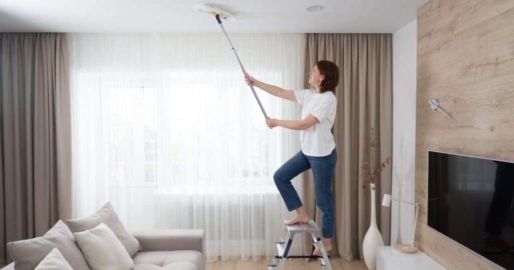 lady dusting ceiling with microfiber mop