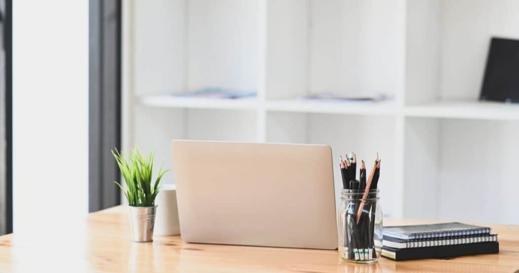 laptop, pens, and planners sitting on the desk of an organizing blogger