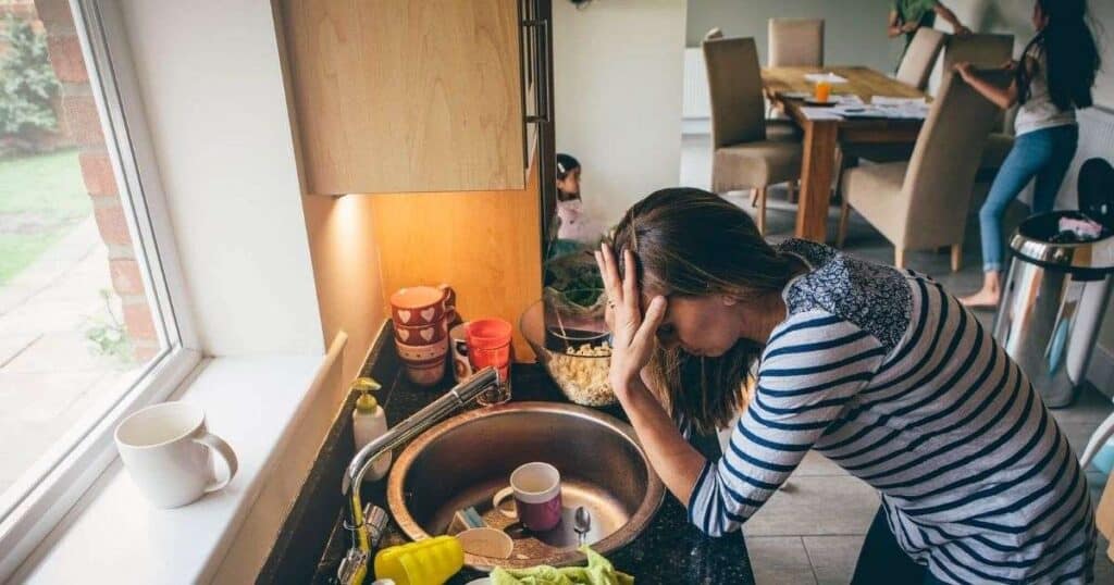 woman so overwhelmed she doesn't know where to start cleaning her messy house